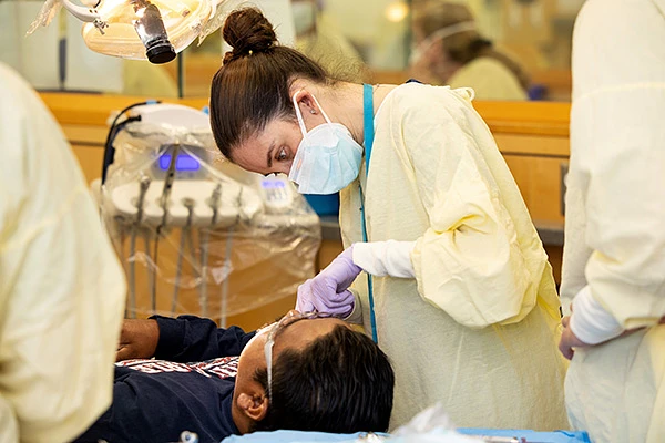 Dentist in yellow gown working on a patient